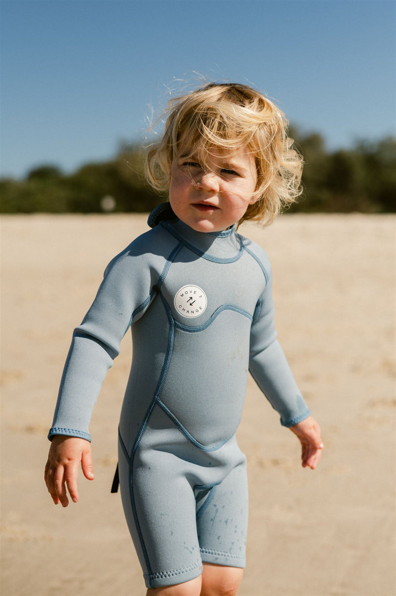 Girl standing on sand watching waves.