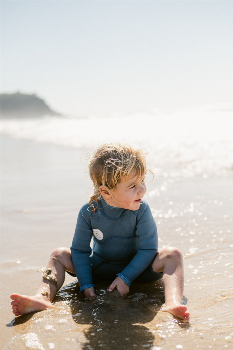 Child happily playing on the shore, in the sand.