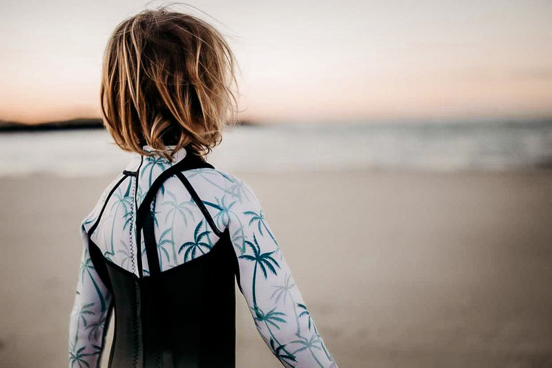 boy looking at surf in kids wetsuit