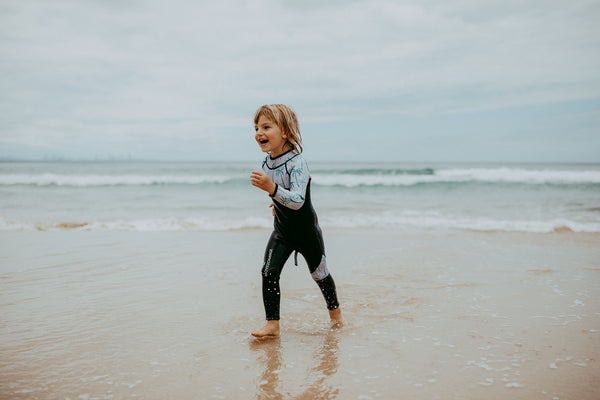 Boy running at beach in Move 2 Change kids wetsuit
