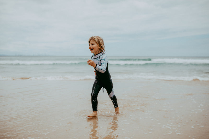 Boy running at beach in Move 2 Change kids wetsuit
