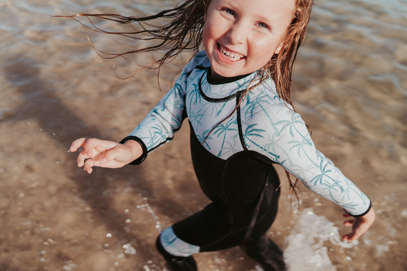 Girl running in water having fun in Move 2 change palm kids wetsuit
