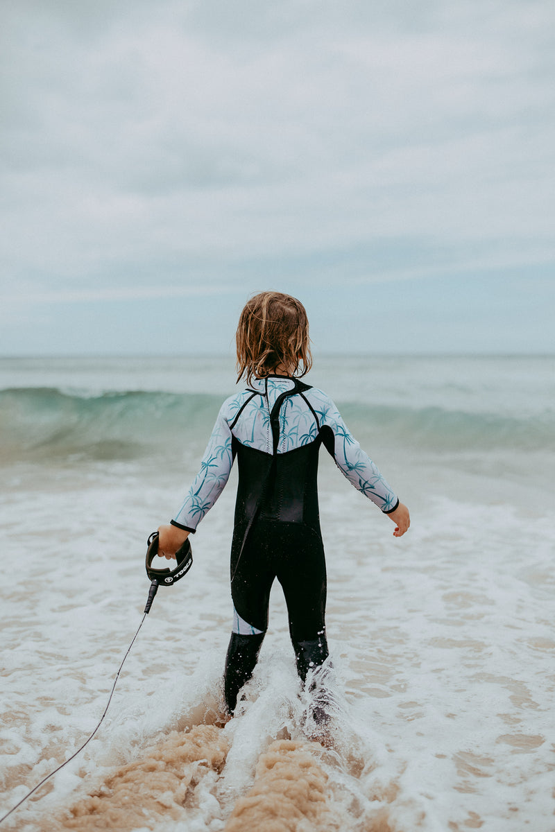 Boy looking at waves in kids full length wetsuit